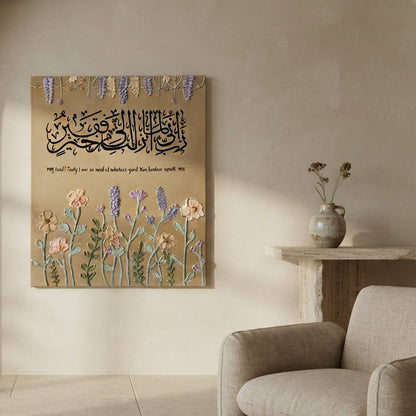 A square wall art print featuring Arabic calligraphy and floral illustrations in soft pastel tones, displayed on a beige wall in a styled interior with a sofa and side table.